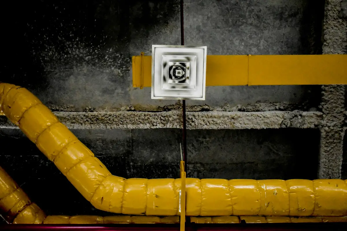 Yellow insulated duct run and a ceiling diffuser with built up dust