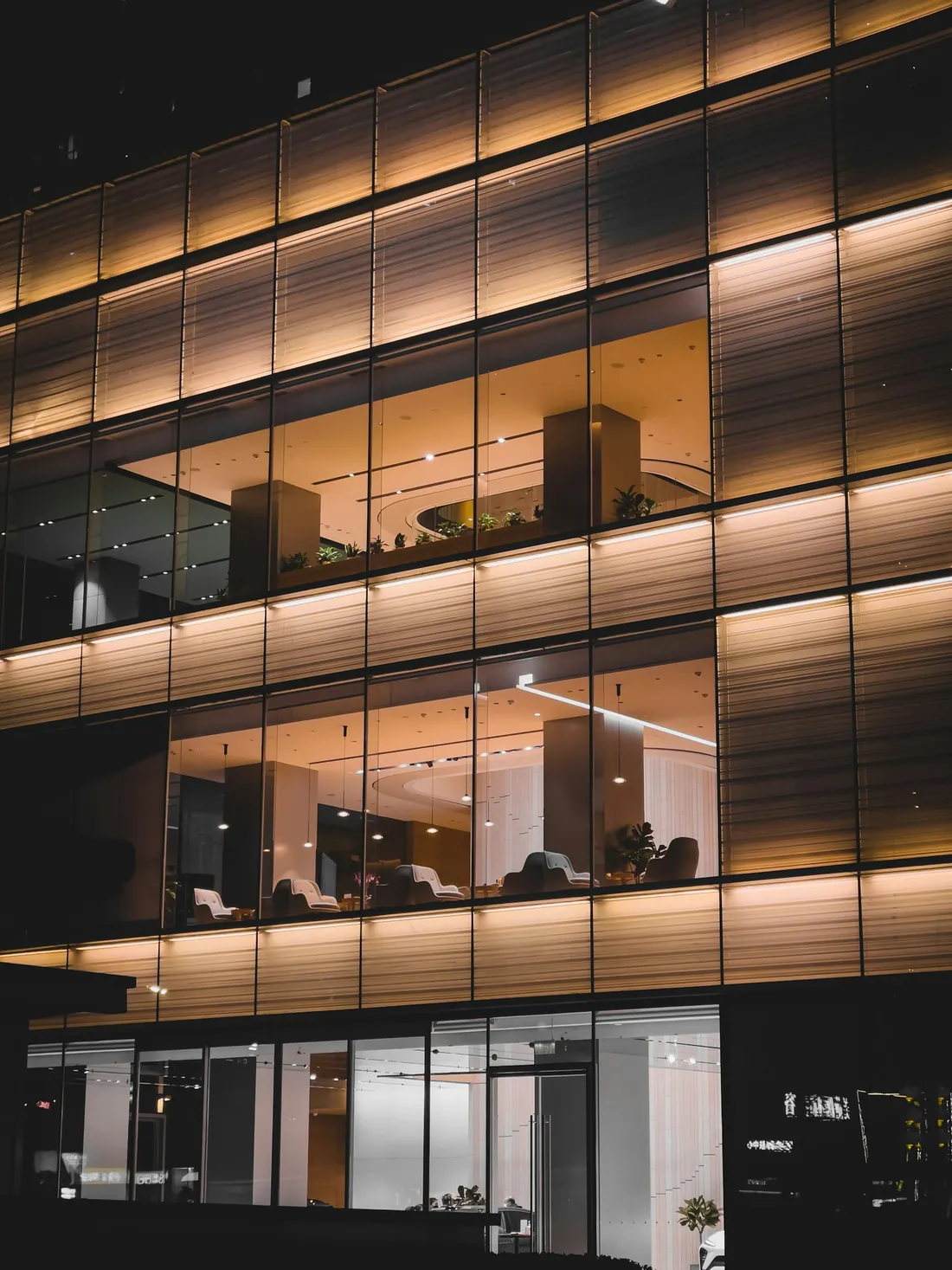 Akşam ışıkları yanan cam cepheli bir ofis binası