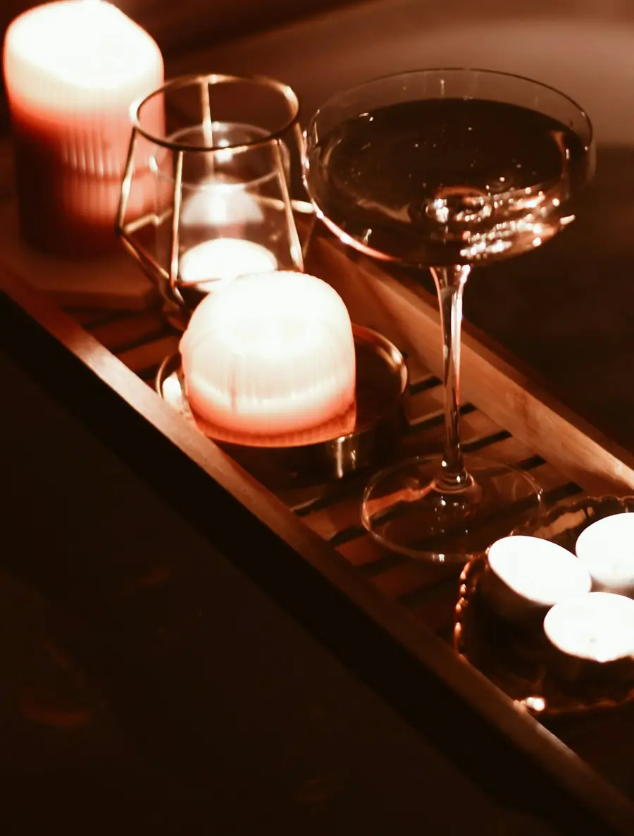 Brennende Kerzen und ein Glas auf einem hölzernen Wannentablett