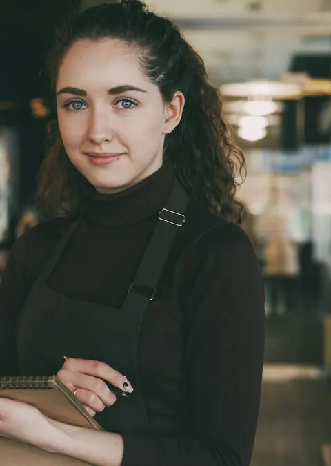 Eine Frau mit Schürze und Notizbuch in einem Restaurant