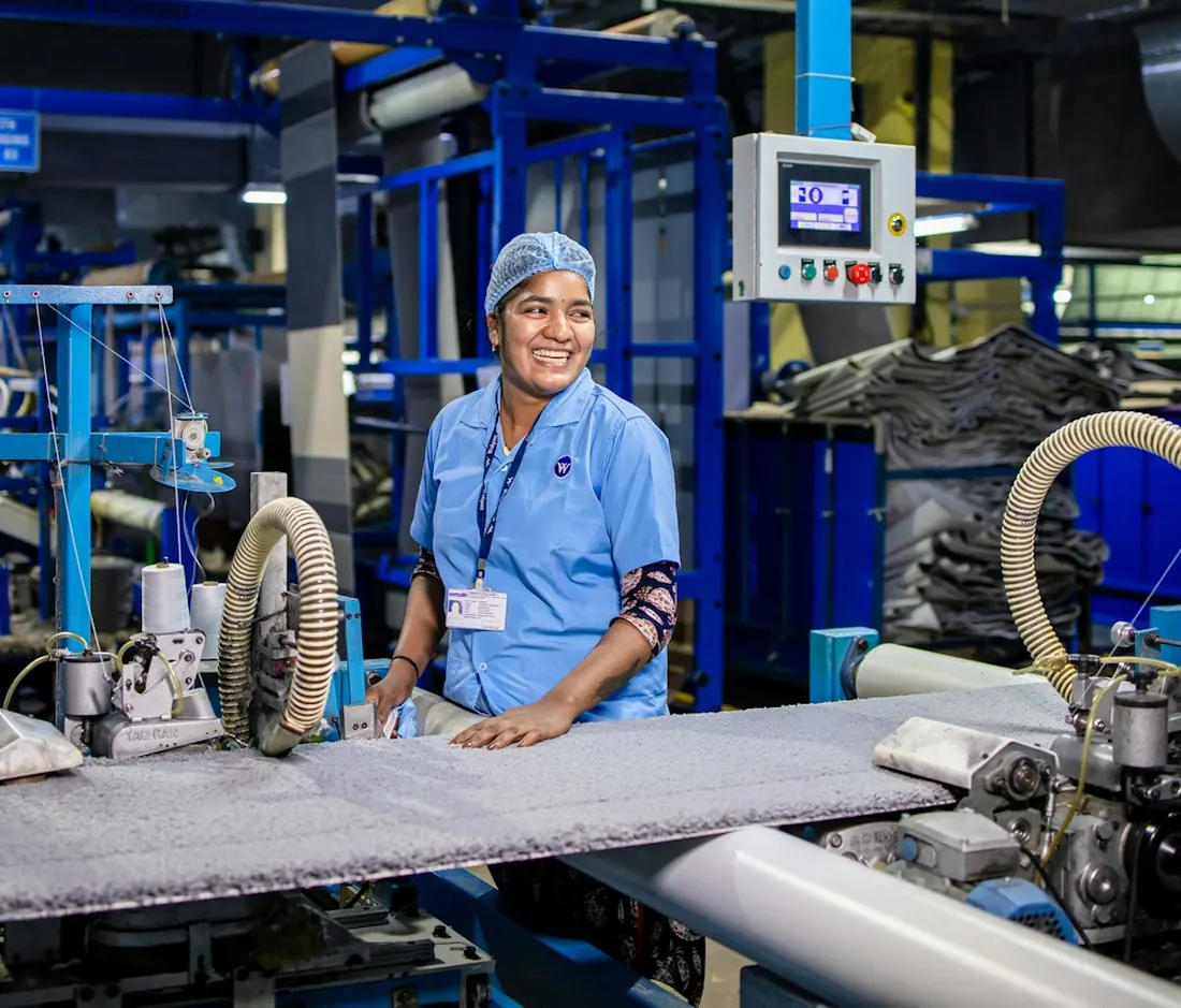 Eine lächelnde Mitarbeiterin an einer Maschine in der Produktion