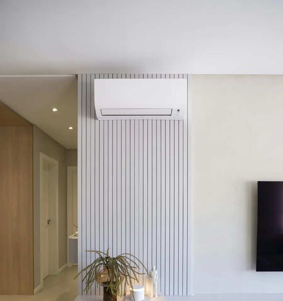 A modern living room with a split system indoor unit above a pale slatted wall