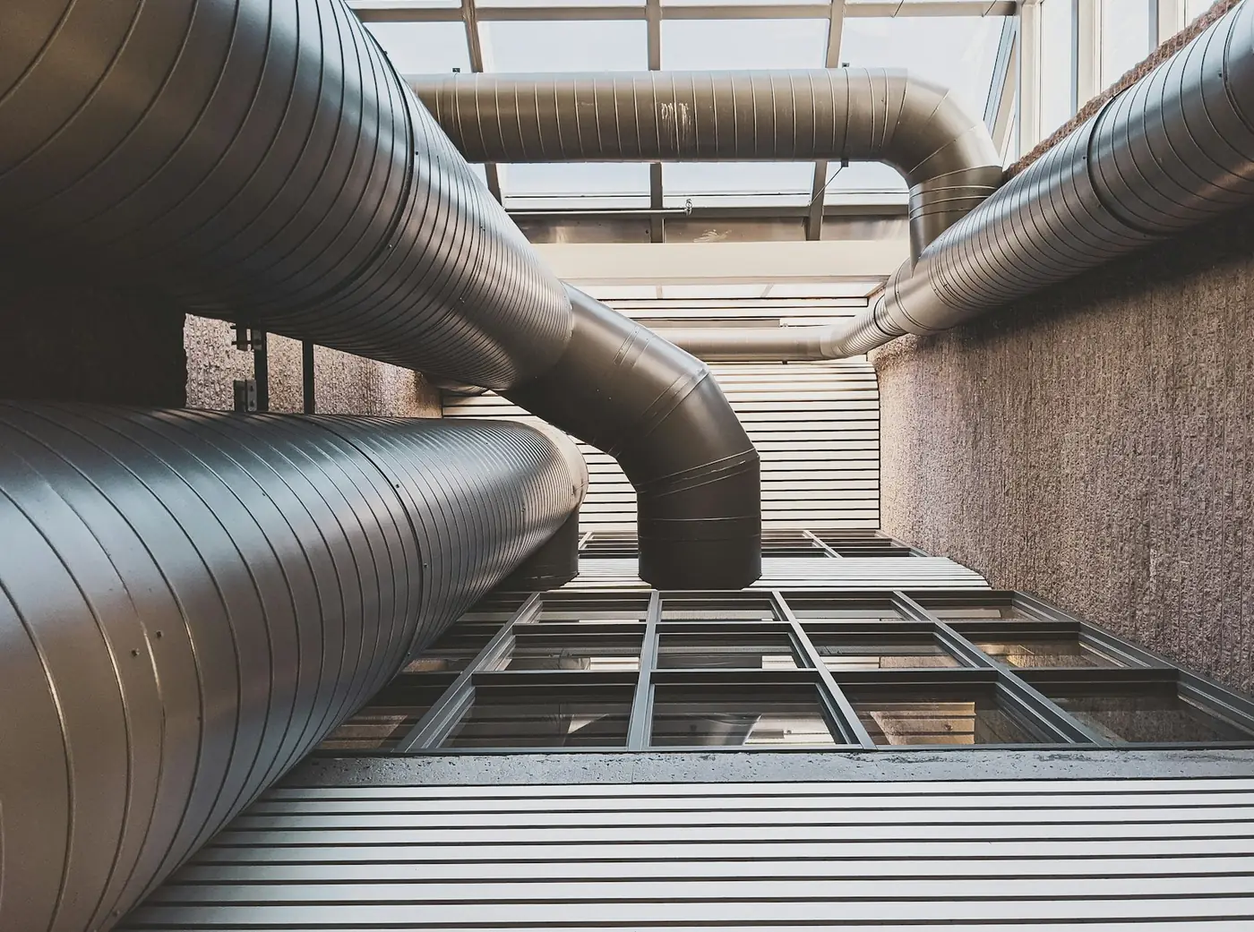 White painted galvanised ventilation ducts hanging from a ceiling