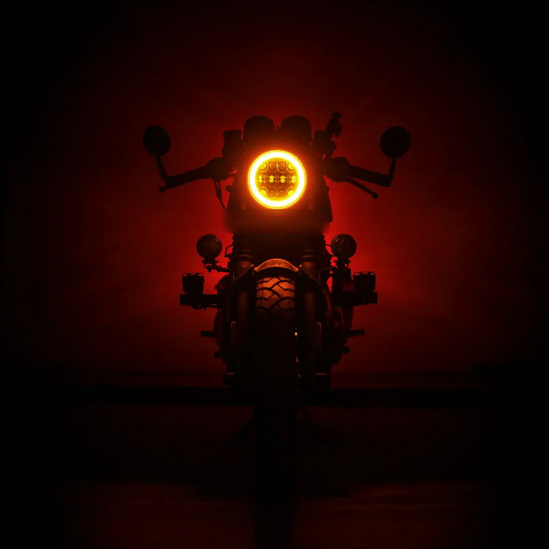 Glowing round headlight and the front outline of a motorcycle in the dark