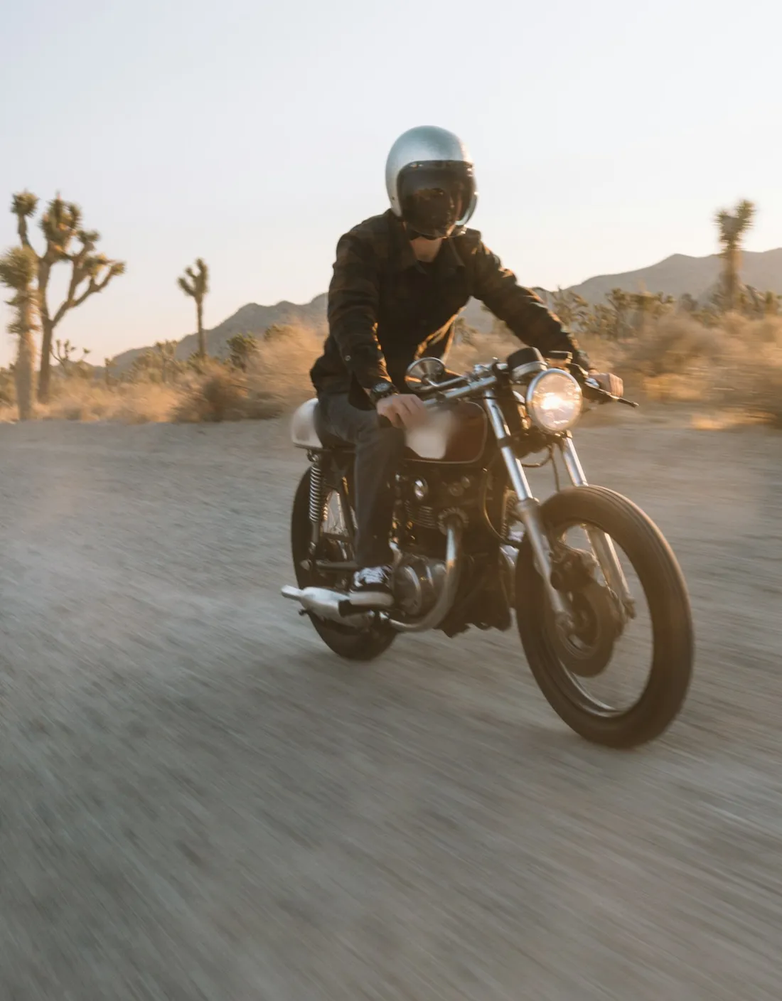 Rider on a classic motorcycle on a desert road at sunset