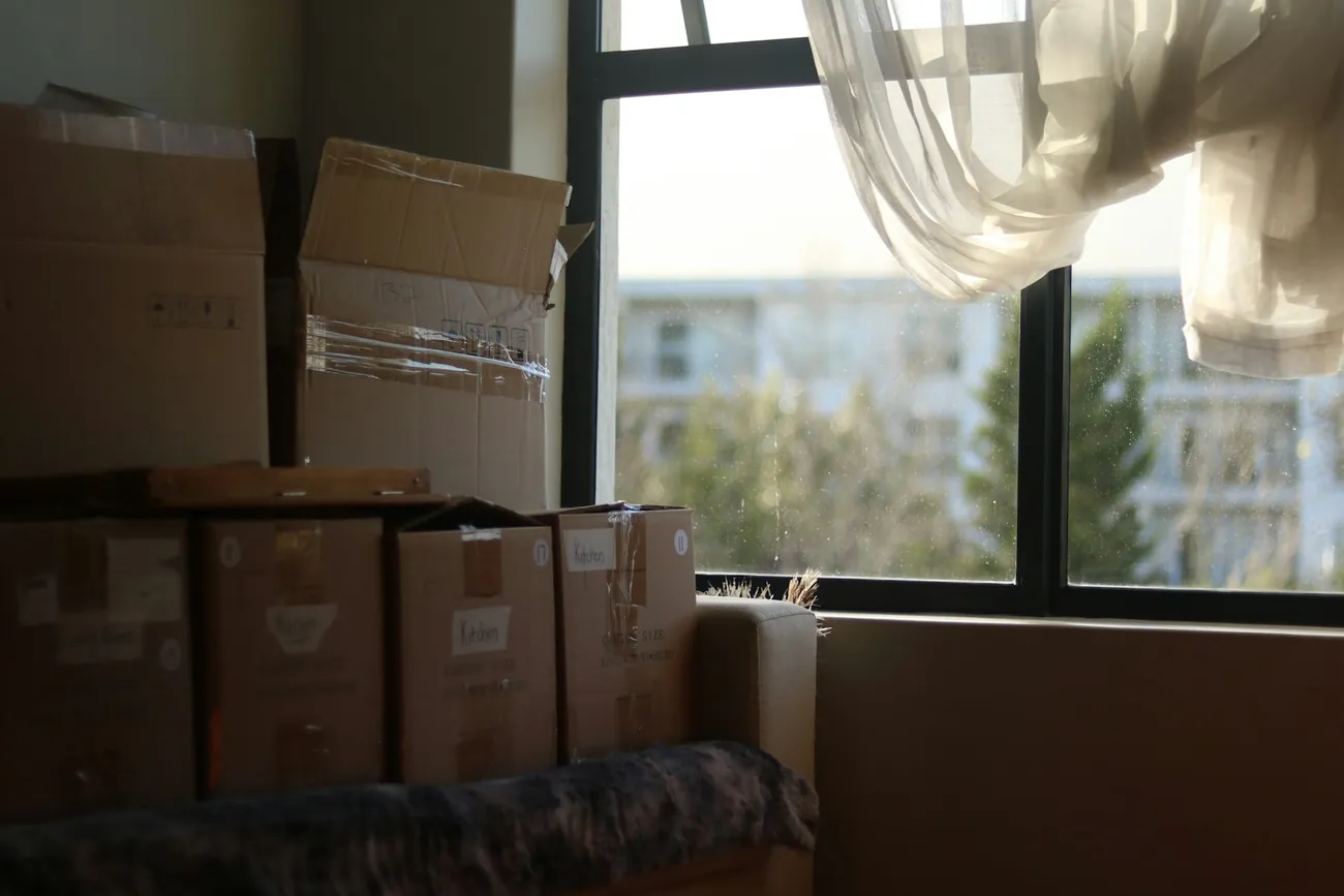 Umzugskartons am Fenster einer neuen Wohnung, bereit zum Auspacken