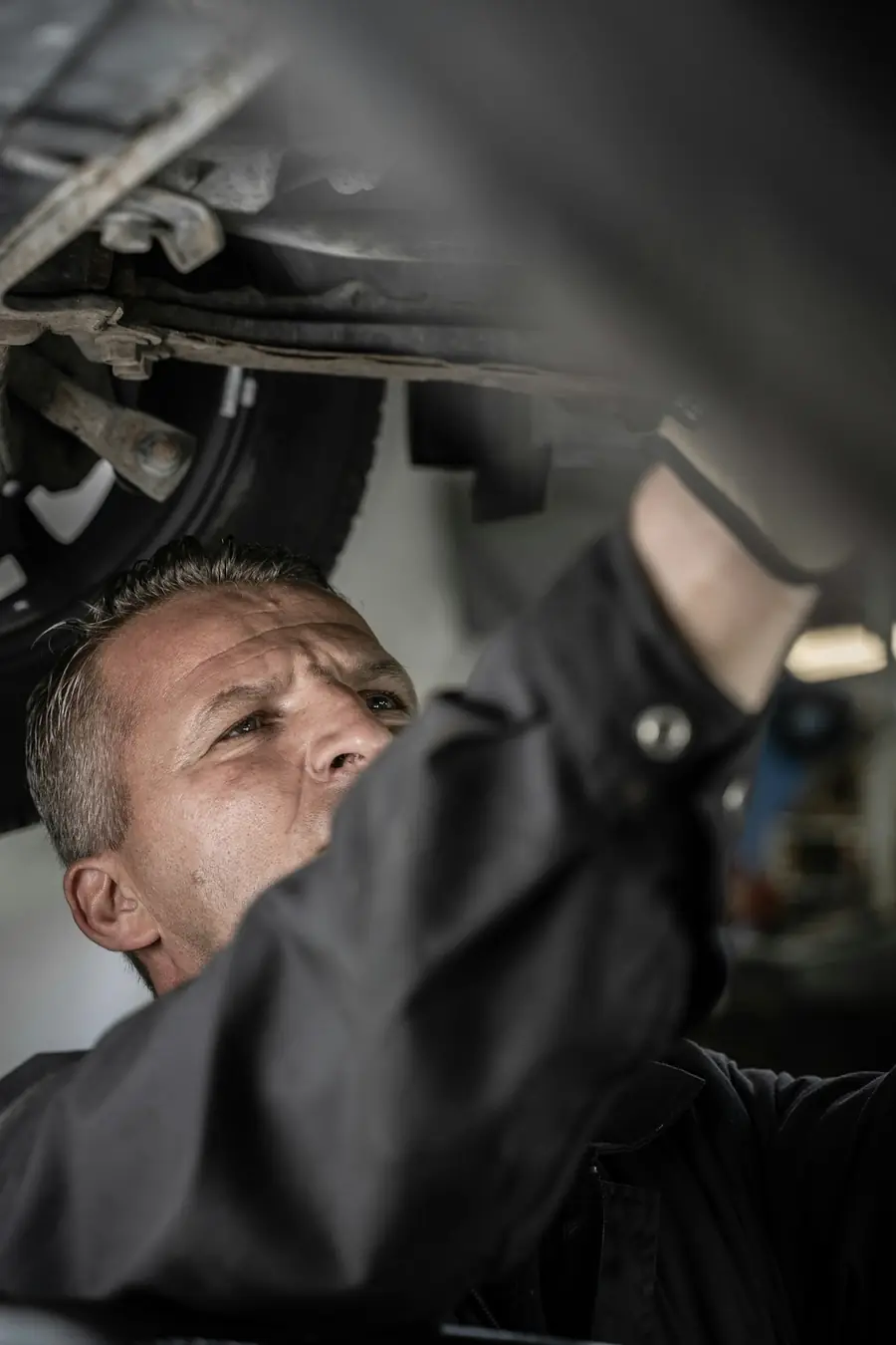 Mechaniker arbeitet unter einem Fahrzeug auf der Hebebühne