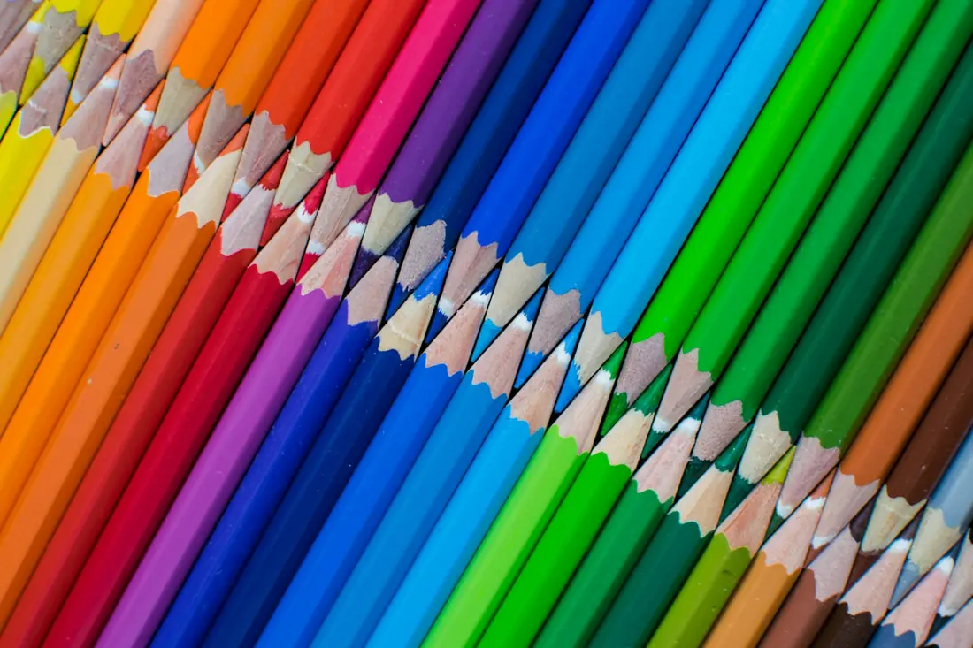 Coloured pencils arranged in a rainbow row