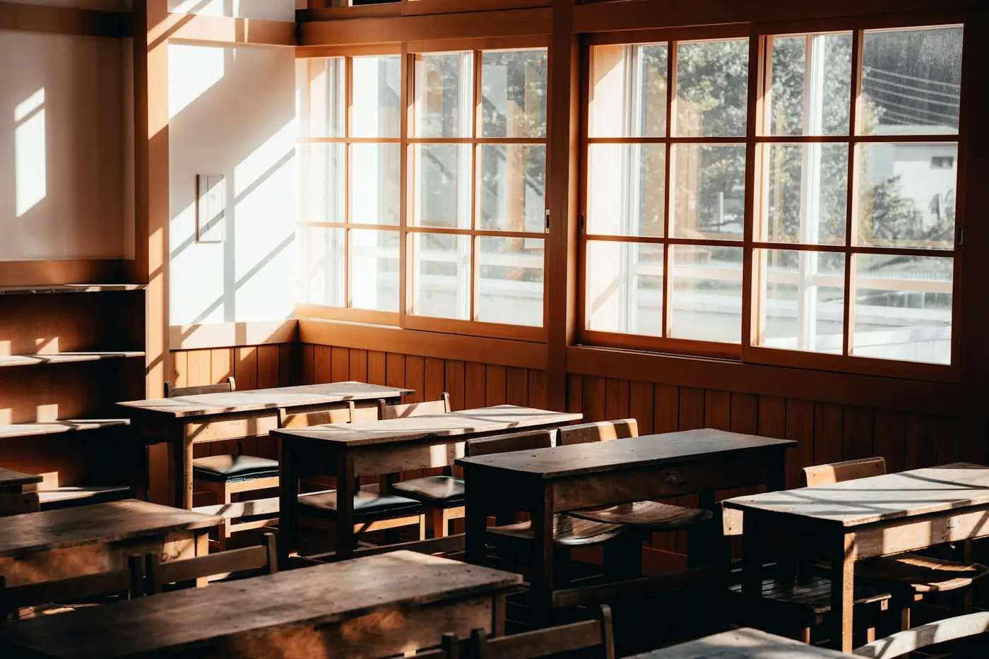 An empty, sunlit classroom with wooden desks