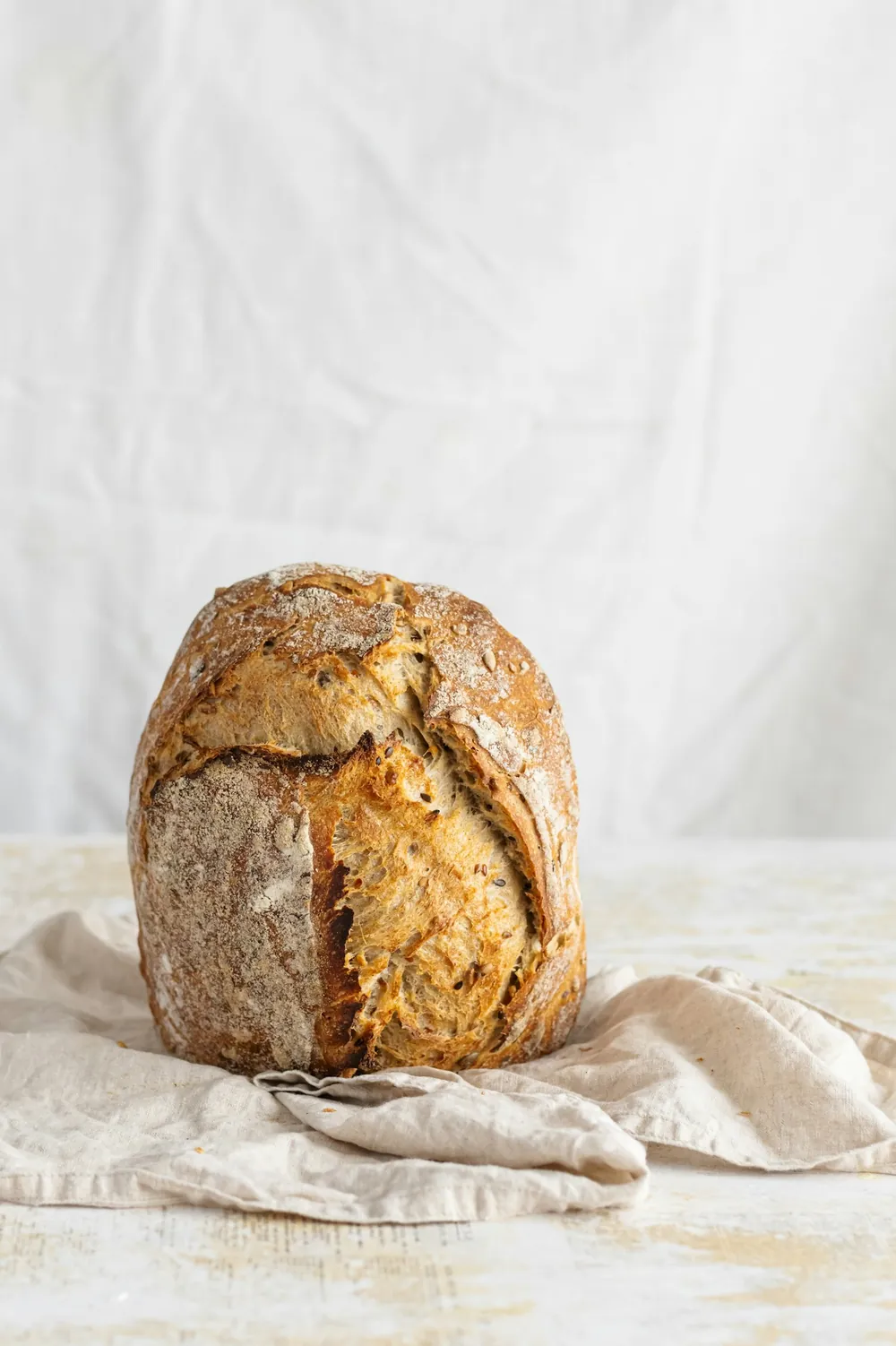 Crusty sourdough loaf resting on a linen cloth