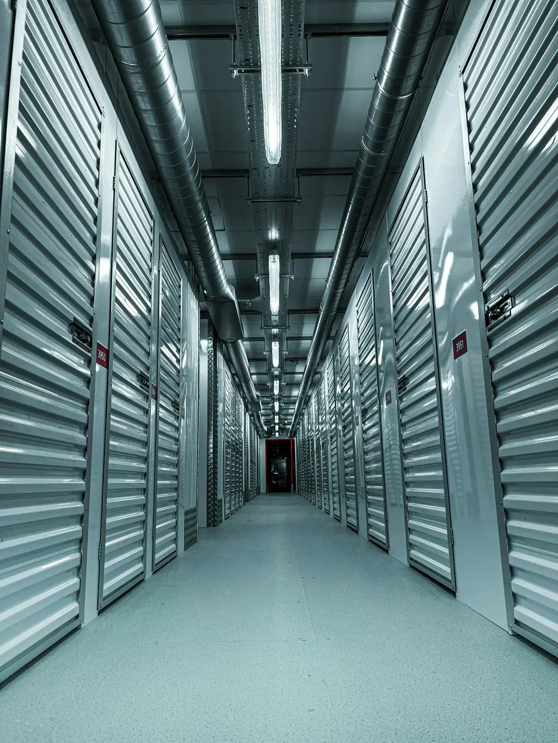 A bright indoor corridor lined with roller shutter storage doors