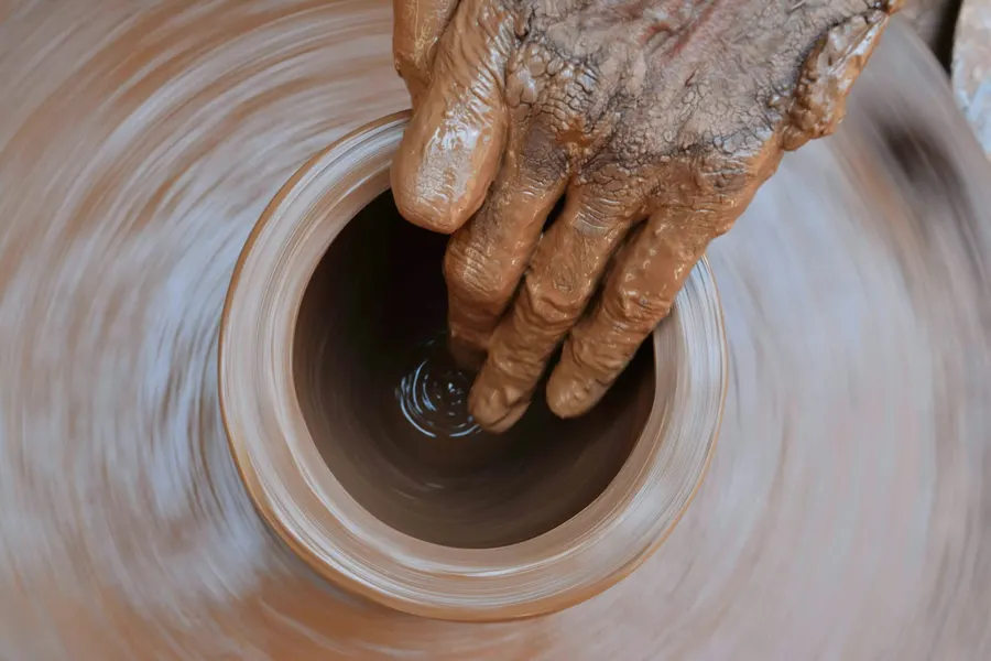 Top view of fingers opening a bowl on a spinning wheel