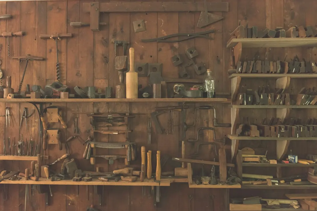 Hand tools arranged on shelves and hooks on a workshop wall