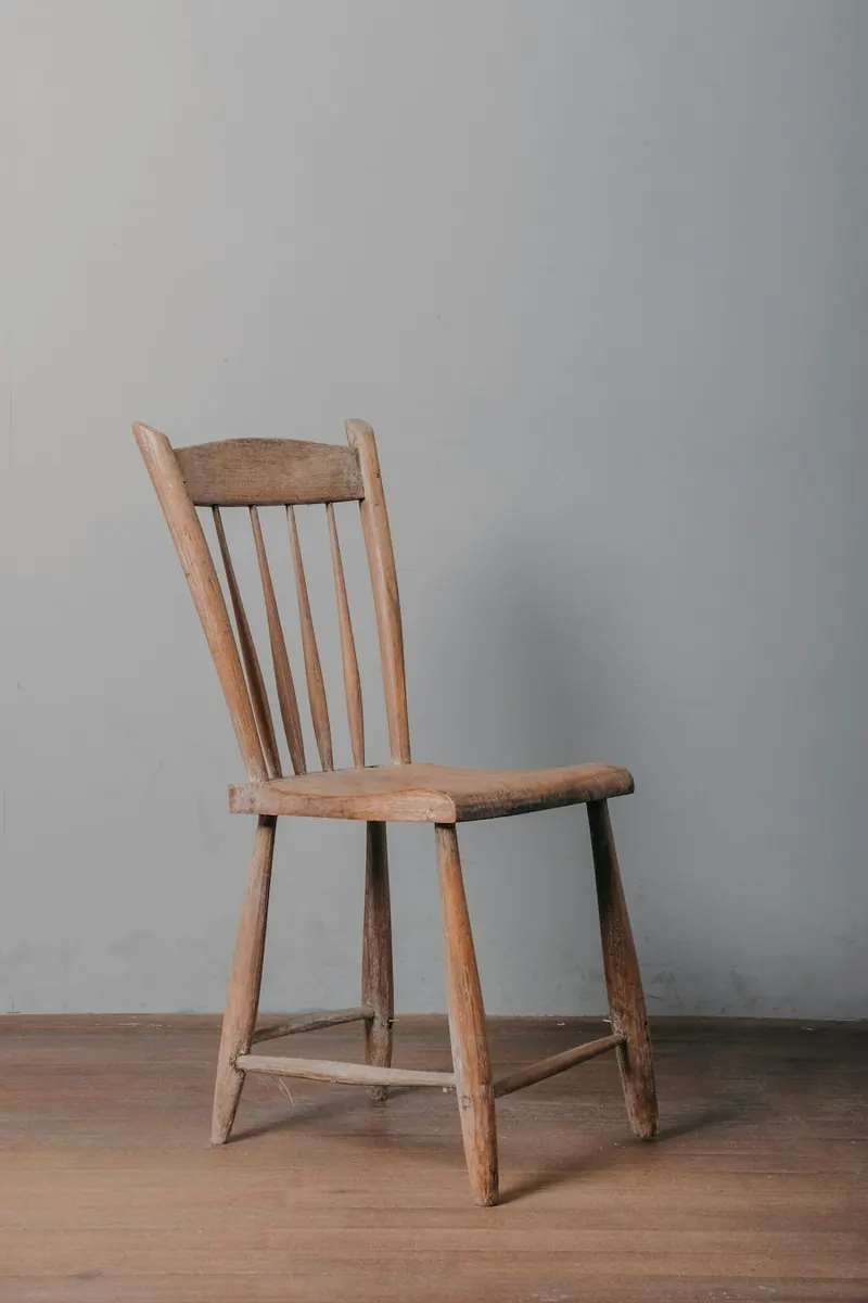 A worn wooden spindle back chair standing on a wooden floor