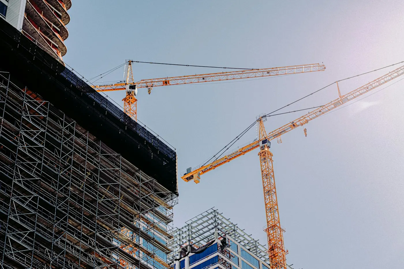 Yellow tower cranes beside a rising building