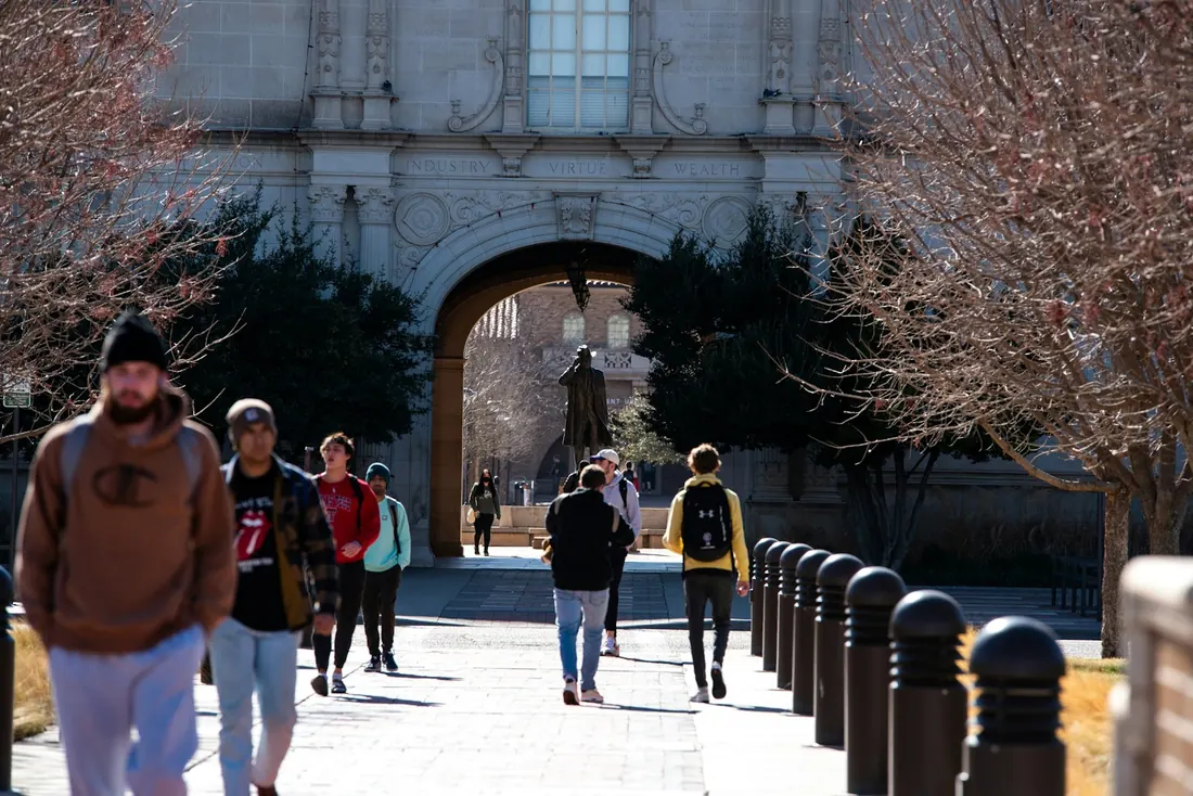Students walking through a stone archway on a university campus