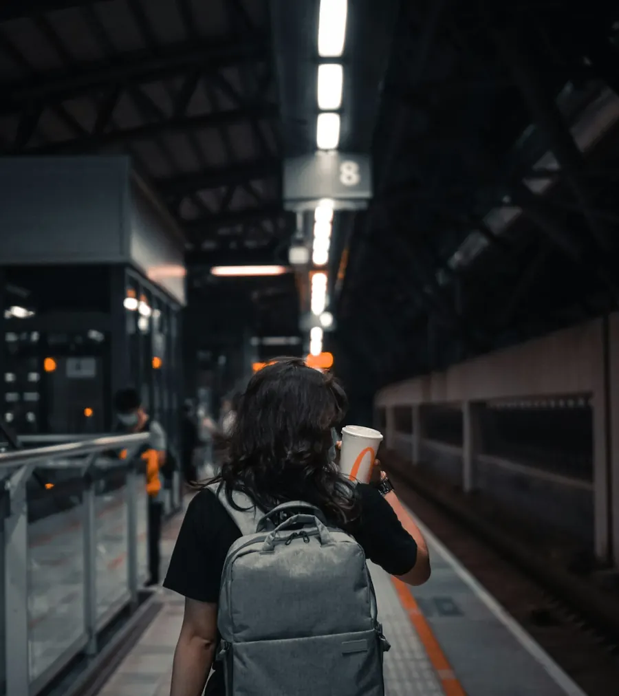 A young traveller with a backpack walking along a train platform